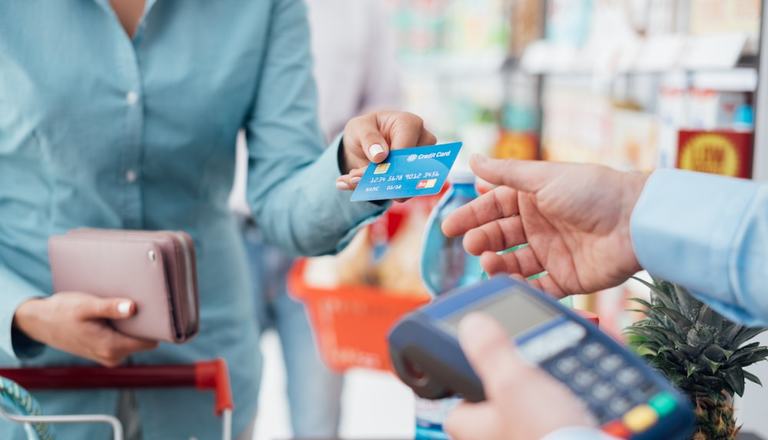 Customer handing over her credit card to the cashier to make a purchase