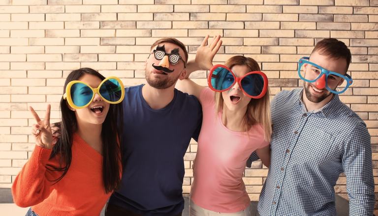 Group of adult friends wearing masks and large novelty glasses, obscuring their identities