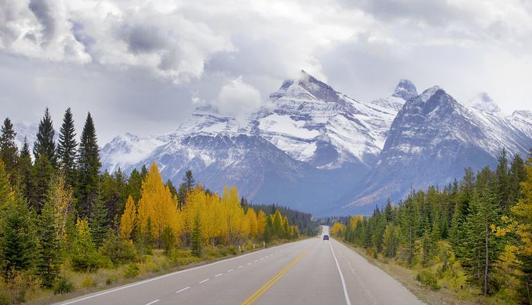 Landscape shot of a scenic Canadian route with highway, mountains and foliage