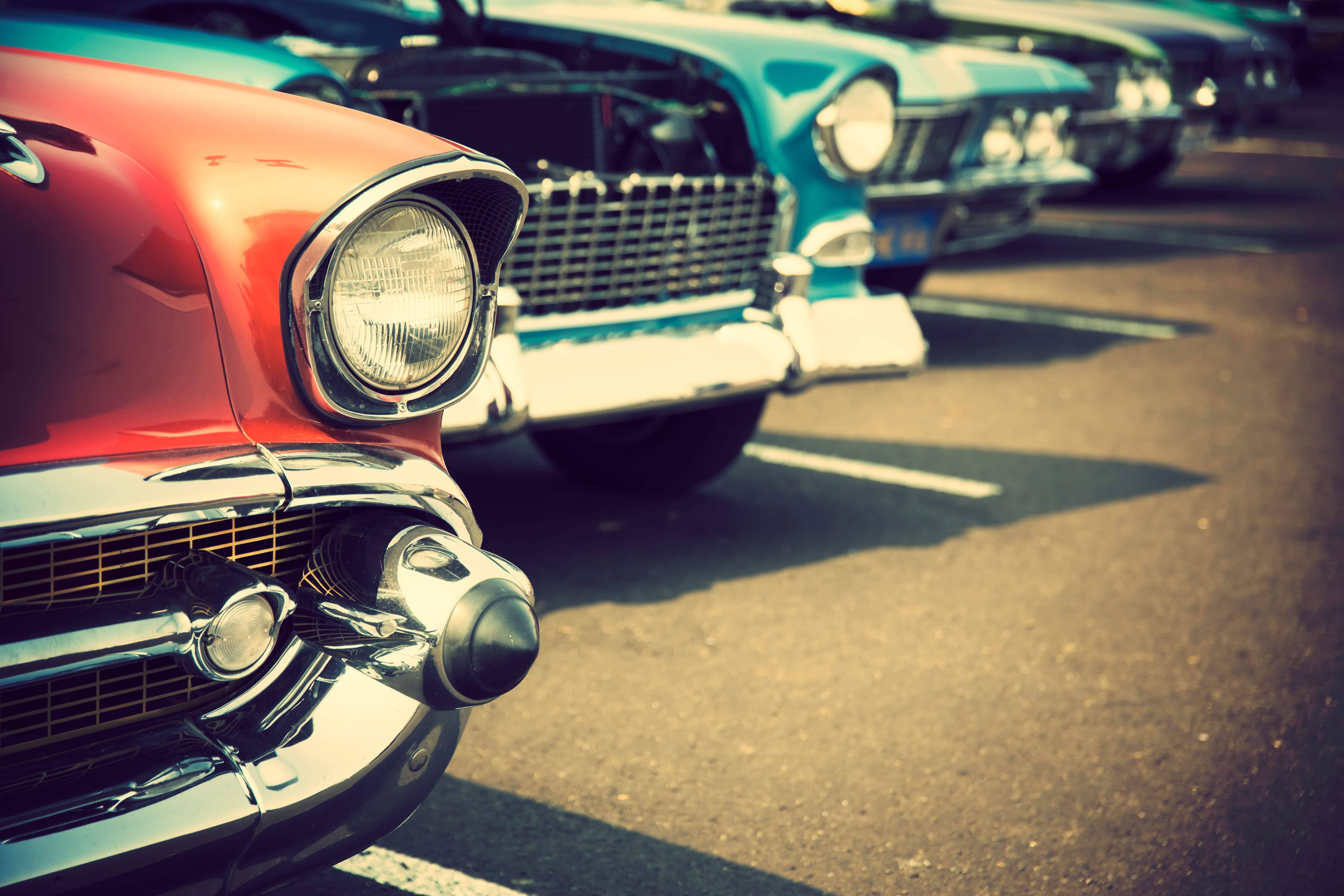 Lower part of classic cars lined up in a row on the left