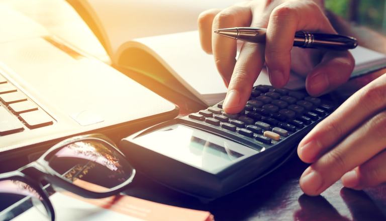 Image of a man's hands working out sums using a calculator