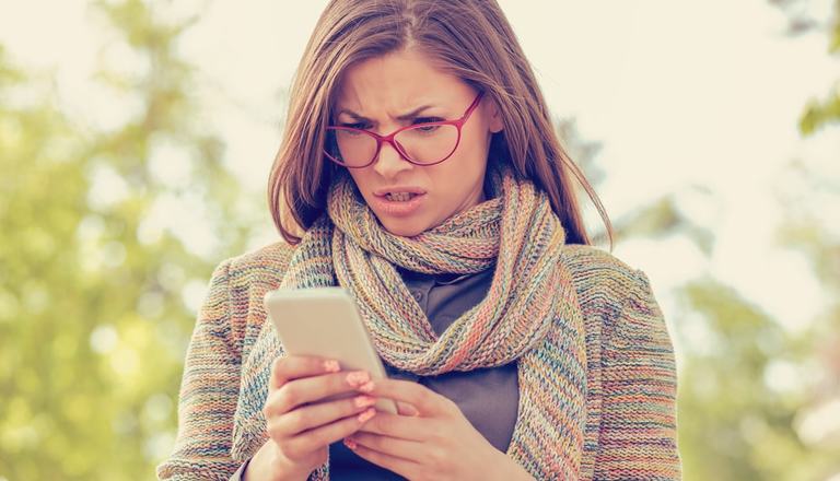 Woman checking her mobile phone with a frustrated look on her face