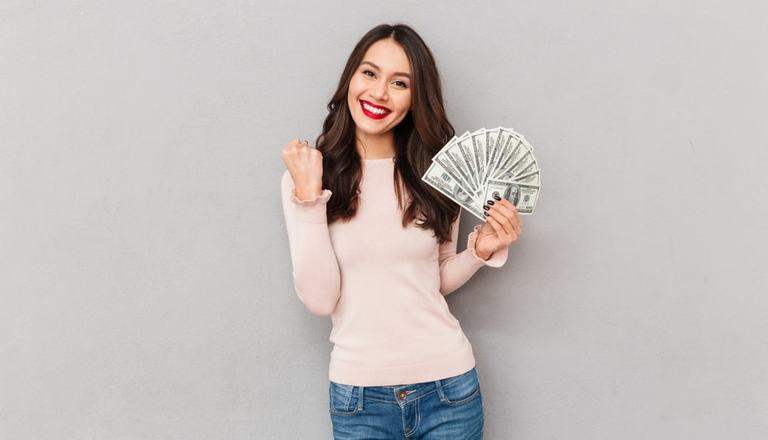 Young lady with a handful of dollar notes and other hand clenched in celebration