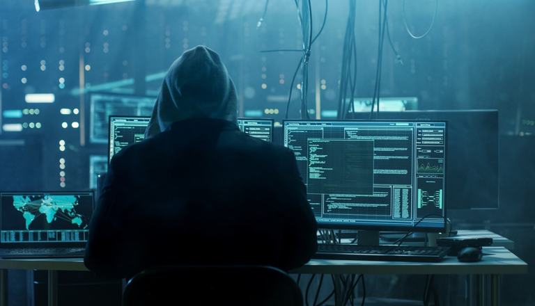 Hooded figure on a computer system hacking