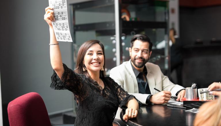 Young woman holding up winning bingo card to the camera and smiling