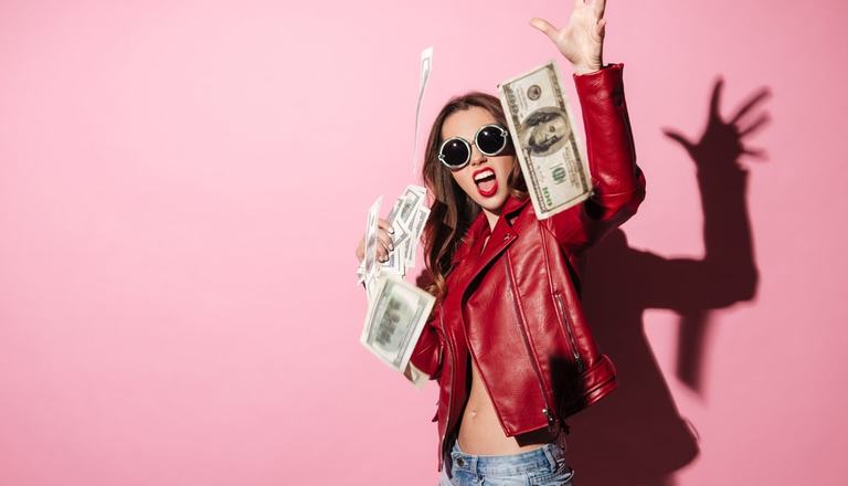 Young woman carelessly throwing dollar bills at the camera