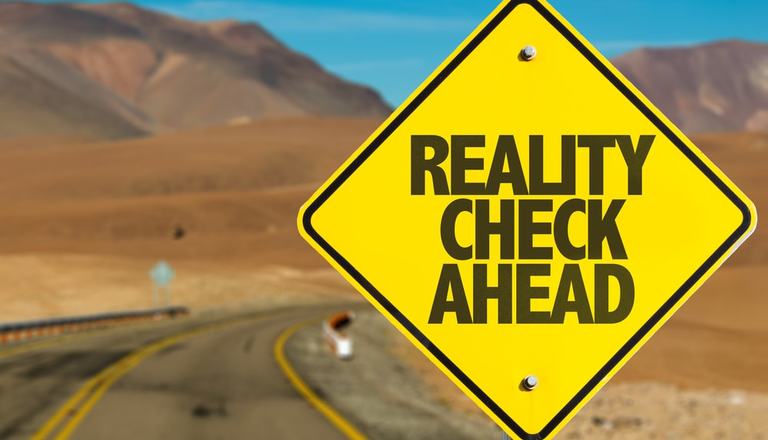 Road sign next to road with the text Reality Check Ahead on it