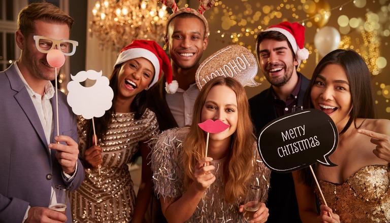 Group of adults celebrating Christmas with festive hats and signs