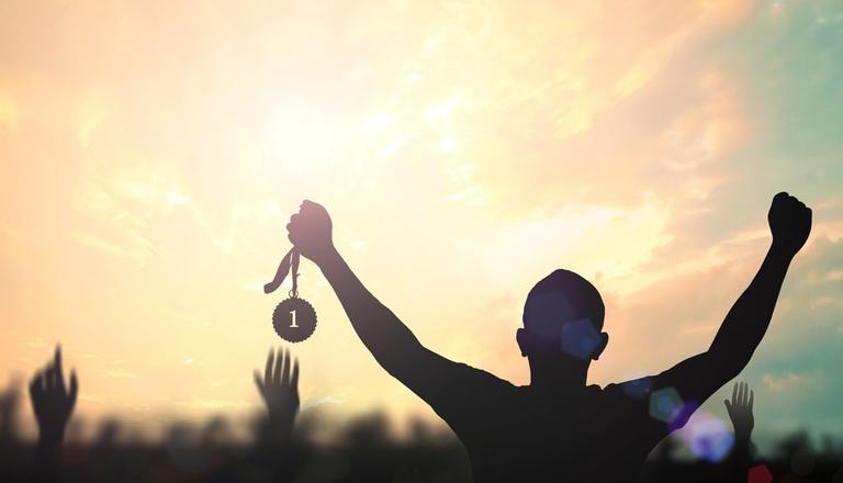 Silhouette of model holding up a No.1 medal with fists clenched in celebration