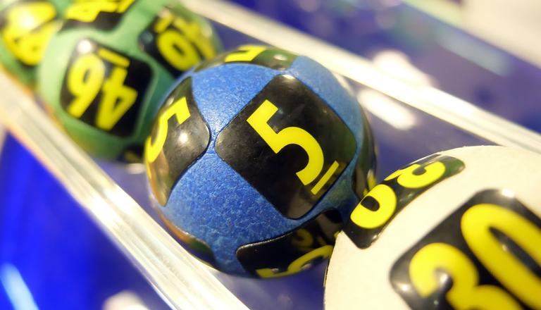 Close-up of three rubber lottery balls being extracted for a draw