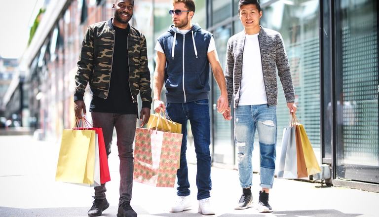 Three fashionable men holding multiple shopping bags on a shopping spree