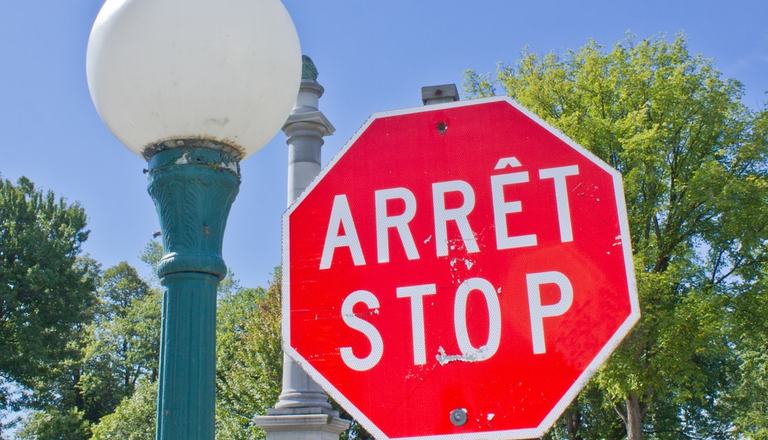Close-up of a red stop sign with French equivalent, Arrete, above the word Stop