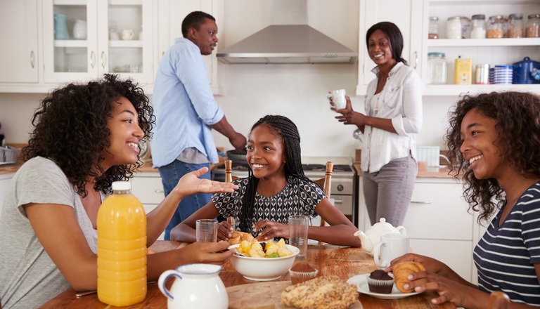 Parents and teenaged children sitting at the table having a discussion