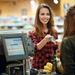 Young lady smiling at and handing her credit card to the cashier who standing behind a counter in a convenience store Thumbnail