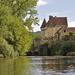 Castle on the right-hand side of a river bank with foliage on the left-hand side and a river in the middle Thumbnail