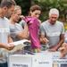 Group of people wearing Volunteer t-shirts, standing outside next to a table with donation boxes on it Thumbnail