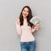 Young lady with a handful of dollar notes and other hand clenched in celebration Thumbnail