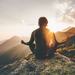 Calm man meditating with legs crossed as he looks over vast mountains Thumbnail