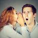 Woman covering mouth with hand whispering to a man who has a shocked expression Thumbnail