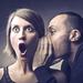 Man telling a woman a secret, cupping his hand against her ear, she has a shocked expression Thumbnail